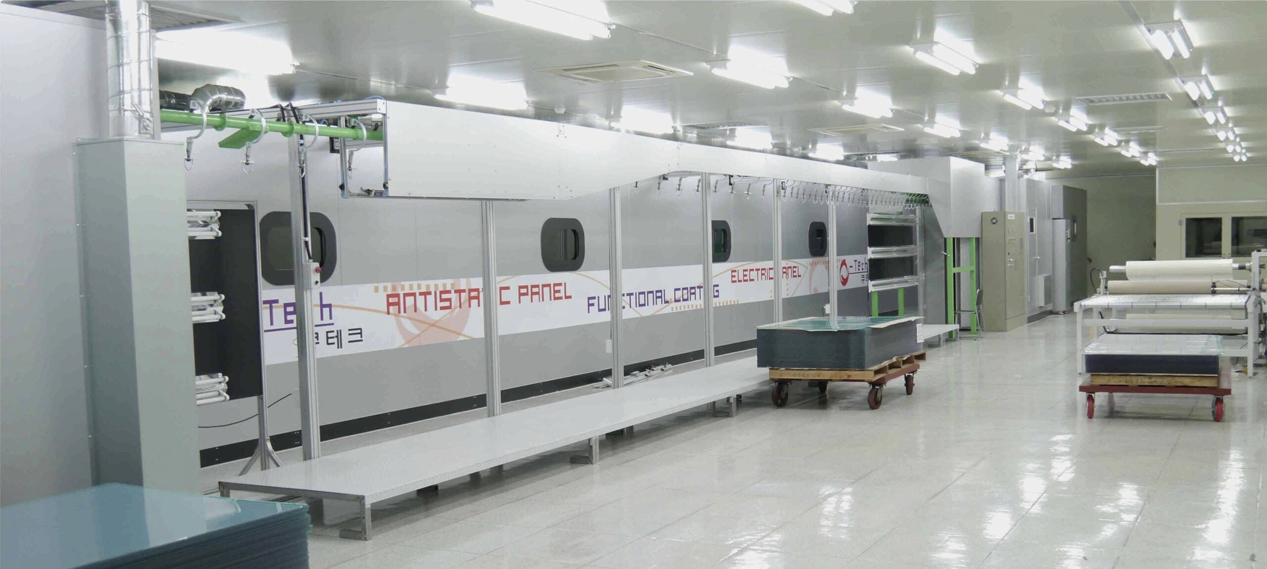 Anti-static coating line at the Q-Tech plant, with panels stacked on carts beside the coating booth.