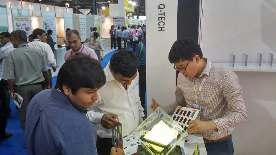 Q-Tech staff explaining coated panel samples to visitors at an overseas exhibition booth